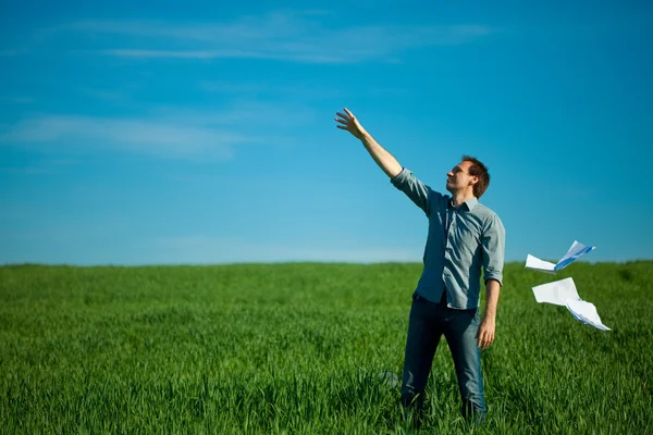 Νεαρός άνδρας που ρίχνουν ένα χαρτί στο πράσινο πεδίο — Φωτογραφία Αρχείου