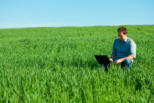 Młody człowiek korzysta z laptopa w polu — Zdjęcie stockowe