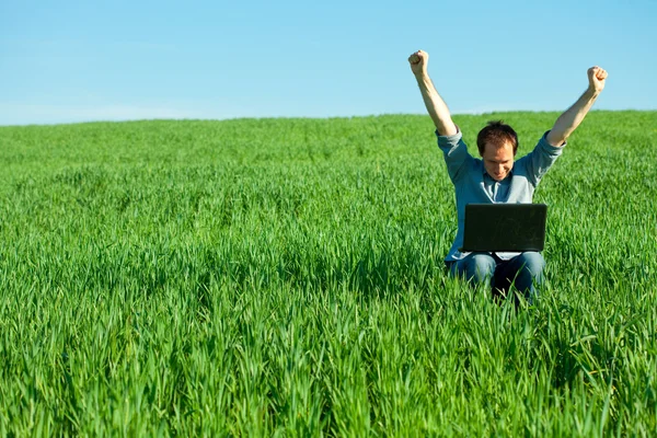 Junger Mann mit Laptop im Feld — Stockfoto