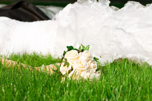 Весільний букет в руці наречена проти сукні, що лежить на — стокове фото