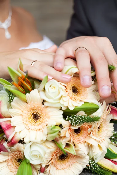 The hands of the bride and groom lying on the bridal bouquet — Stock Photo, Image