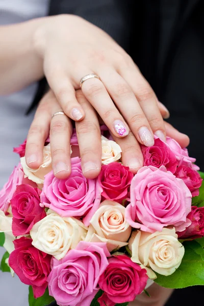 Les mains des mariés couchées sur le bouquet nuptial — Photo