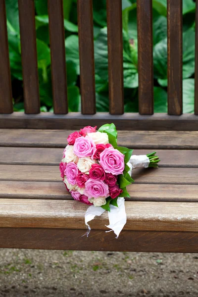 Beautiful bridal bouquet lying on the wooden benches — Stock Photo, Image