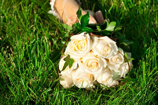Bridal bouquet to the bride's hand lying on green grass — Stock Photo, Image