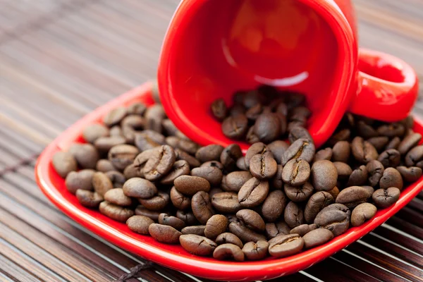 Tasse et soucoupe et grains de café sur un tapis de bambou — Photo