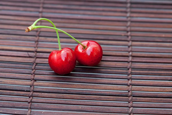 Two cherries on a bamboo mat — Stok fotoğraf