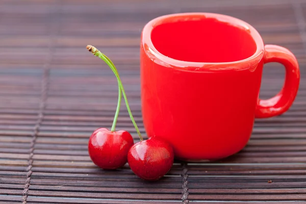 Cherry cup on bamboo mat — Stock Photo, Image