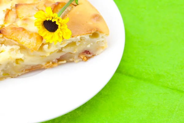 Piece of apple pie and a flower lying on the green cloth — Stock Photo, Image