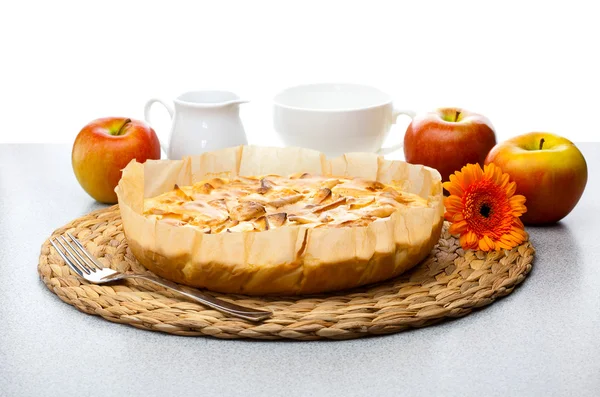 Натюрморт из яблочного пирога, кувшин с молоком Герберы и чашка — стоковое фото
