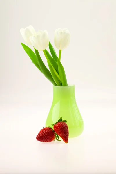 Vaas met tulpen en aardbeien op witte geïsoleerd — Stockfoto