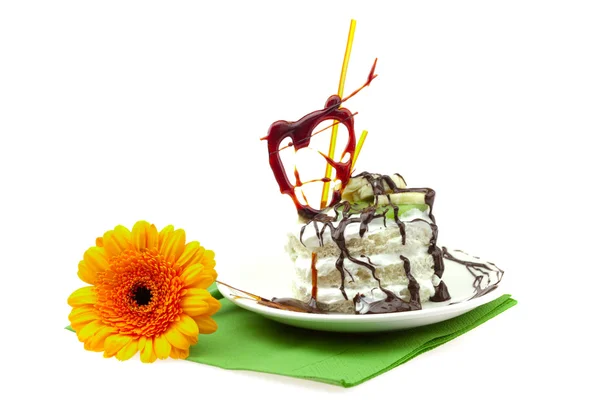 ケーキ クリーム キャラメルの心臓と緑の布の上に横たわるガーベラ — ストック写真