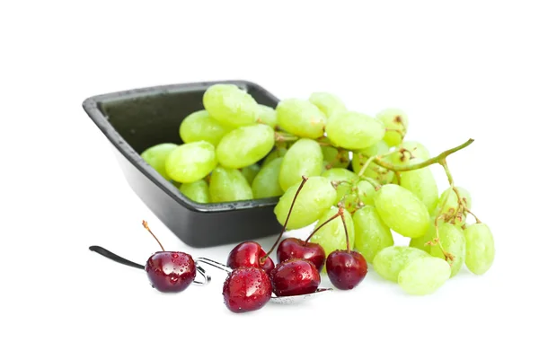 Cherries with drops of water in a spoon and a bowl of grapes iso — Stock Photo, Image
