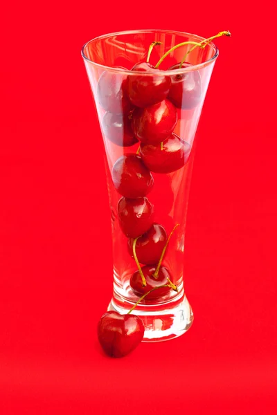 Vidro de cereja sobre um fundo vermelho — Fotografia de Stock