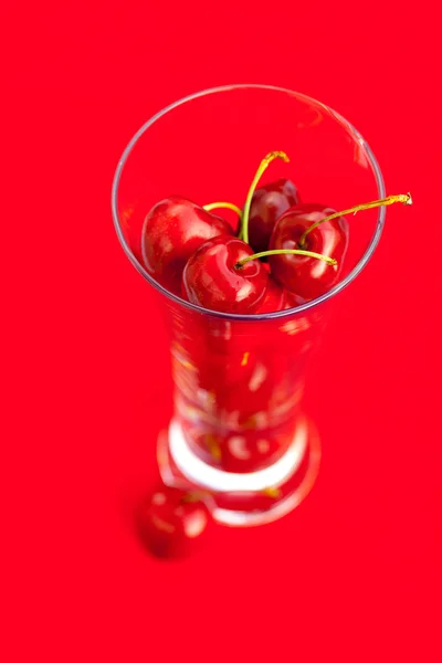 Стакан вишни на красном фоне — стоковое фото