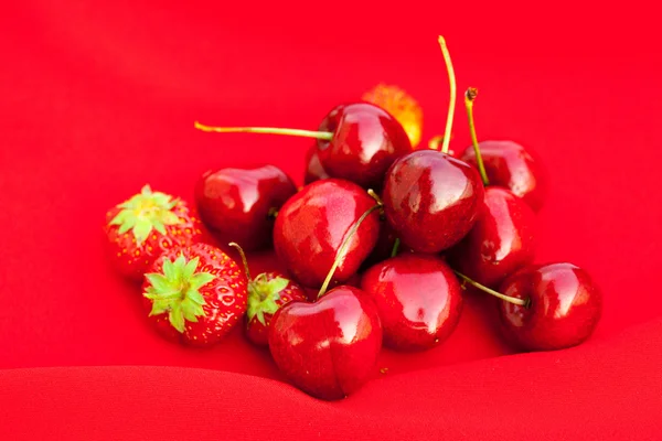 Cereza y fresa sobre fondo rojo —  Fotos de Stock