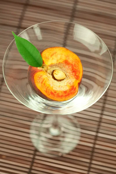 Persik dalam gelas martini di tikar bambu — Stok Foto