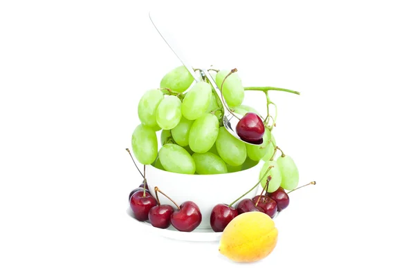 Cup of grapes, cherries and apricots isolated on white — Stock Photo, Image