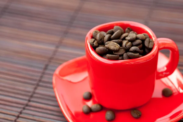 Cup and saucer and coffee beans on a bamboo mat — Stock Photo, Image