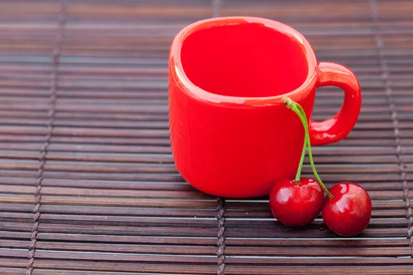 Cherry, cup on bamboo mat — стоковое фото