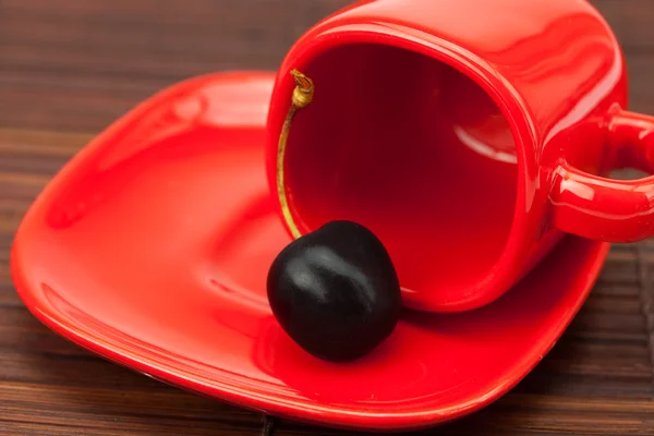 Red cup and a cherry on a bamboo mat — Stock Photo, Image