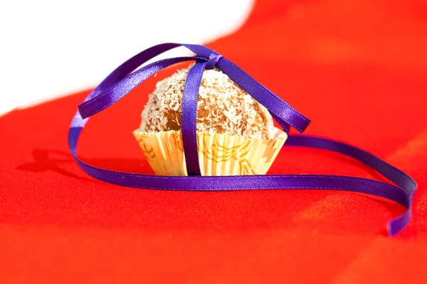 Gâteau à la noix de coco avec un ruban attaché sur un fond rouge — Photo