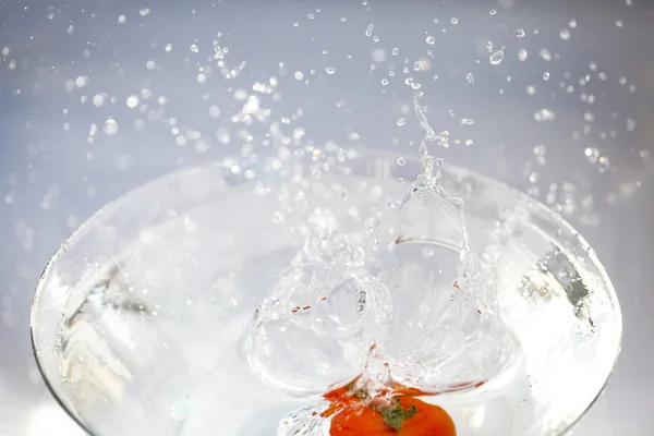 Tomates con salpicaduras de agua en un recipiente de vidrio — Foto de Stock