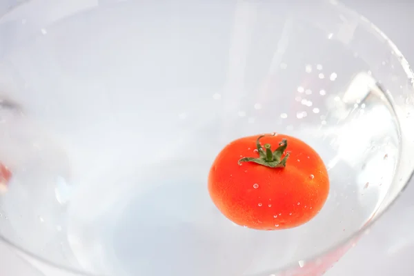 Tomates com salpicos de água em uma tigela de vidro — Fotografia de Stock