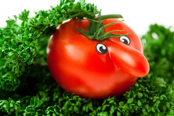 Tomato with eyes lying on a plate with greens — Stock Photo, Image