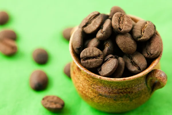 Piccola pentola di chicchi di caffè sulla materia verde — Foto Stock