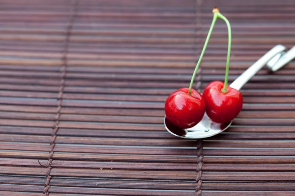 Cherry v lžíci na bambusové rohoži — Stock fotografie