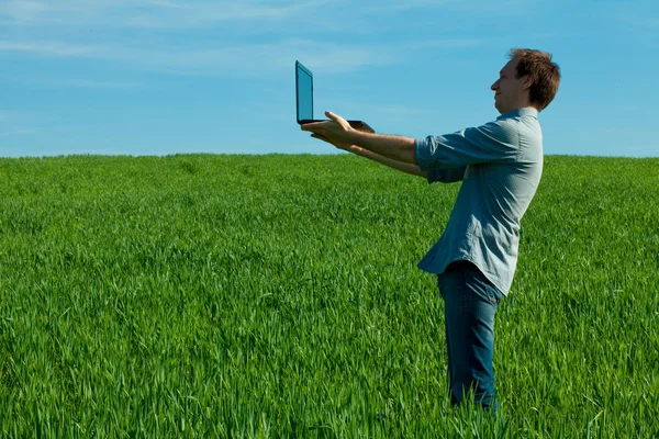 Человек с ноутбуком, стоящий в поле — стоковое фото