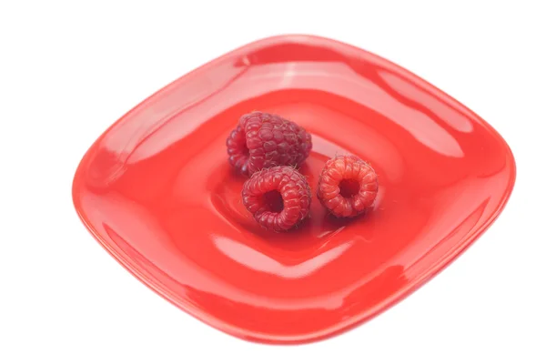 Raspberries in a red saucer isolated on white — Stock Photo, Image