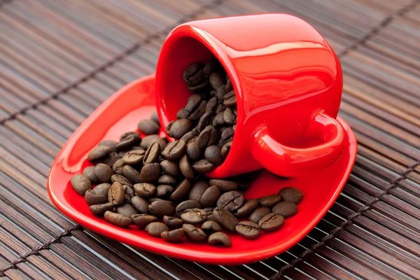 Granos de café en una taza en una estera de bambú —  Fotos de Stock