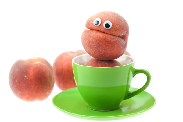 Peach with eyes in the cup and saucer isolated on white — Stock Photo, Image