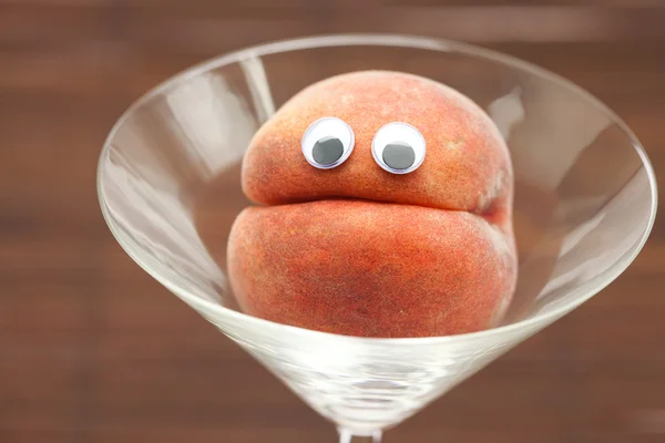 Pfirsich mit Augen im Glas Martini auf einer Bambusmatte — Stockfoto