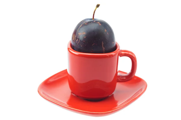 Plum in a cup and saucer isolated on white — Stock Photo, Image
