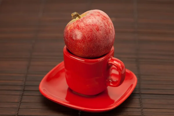 Cup, saucer and apples on a bamboo mat — Stock Photo, Image