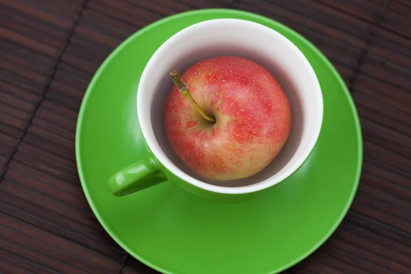 Κύπελλο και πιατάκι, μήλα σε ένα χαλί μπαμπού — Φωτογραφία Αρχείου