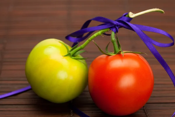 Red and green tomatoes tied a ribbon on a bamboo mat — Stock Photo, Image