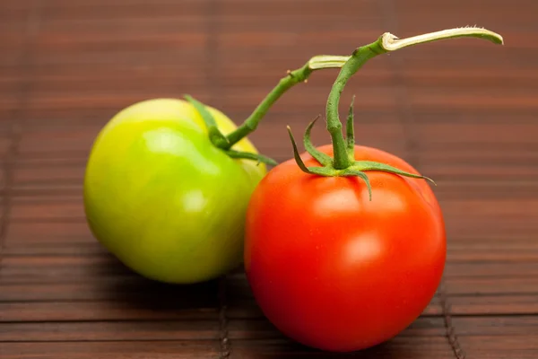 Red and green tomatoes on a bamboo mat — Stock Photo, Image
