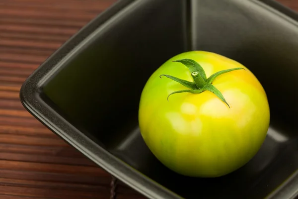 Gröna tomater i en skål på en bambu matta — Stockfoto