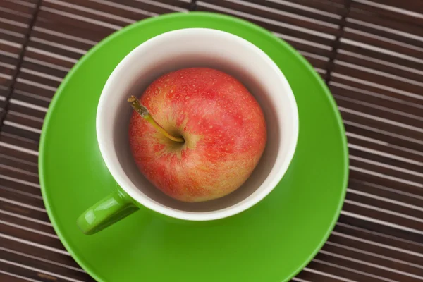 Kupa, fincan tabağı ve bambu hasır üzerinde elma — Stok fotoğraf