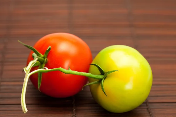 Tomates rojos y verdes en una estera de bambú — Foto de Stock