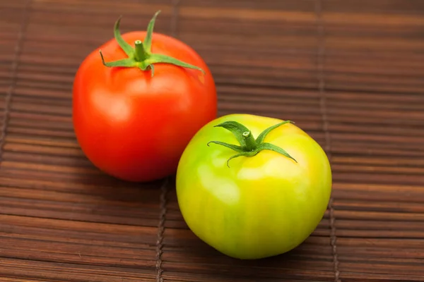 Tomates verdes e vermelhos em uma esteira de bambu — Fotografia de Stock