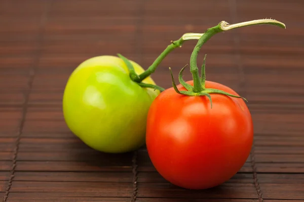 Rode en groene tomaten op een bamboe-mat — Stockfoto