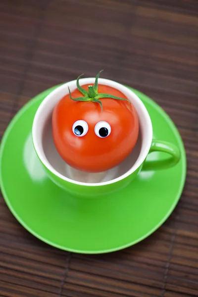 Tomate avec les yeux dans la tasse sur un tapis de bambou — Photo