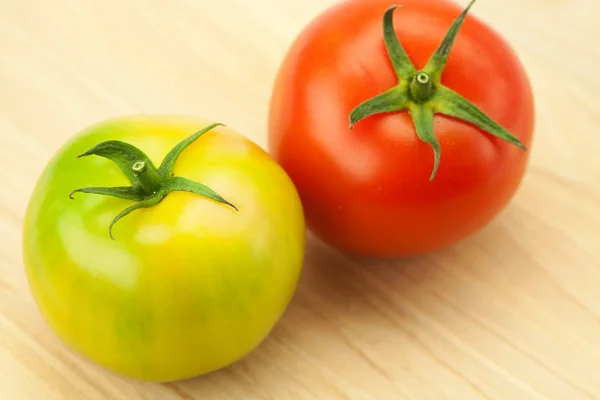 Tomates verdes e vermelhos em uma placa de corte — Fotografia de Stock