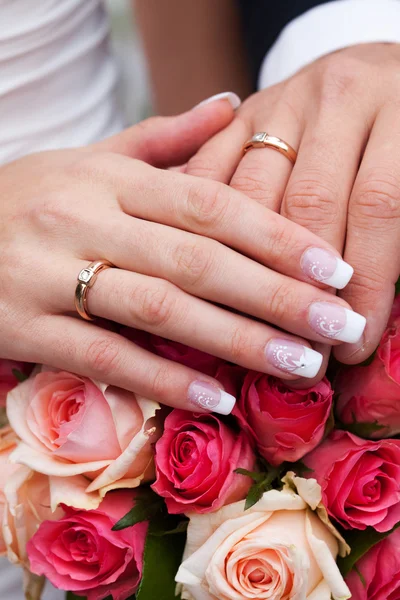 Händerna på bruden och brudgummen med ringar liggande på buketten — Stockfoto
