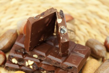 Bar of chocolate and nuts on a wicker mat