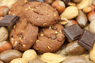 Oatmeal cookies, chocolate and nuts on a wicker mat clipart